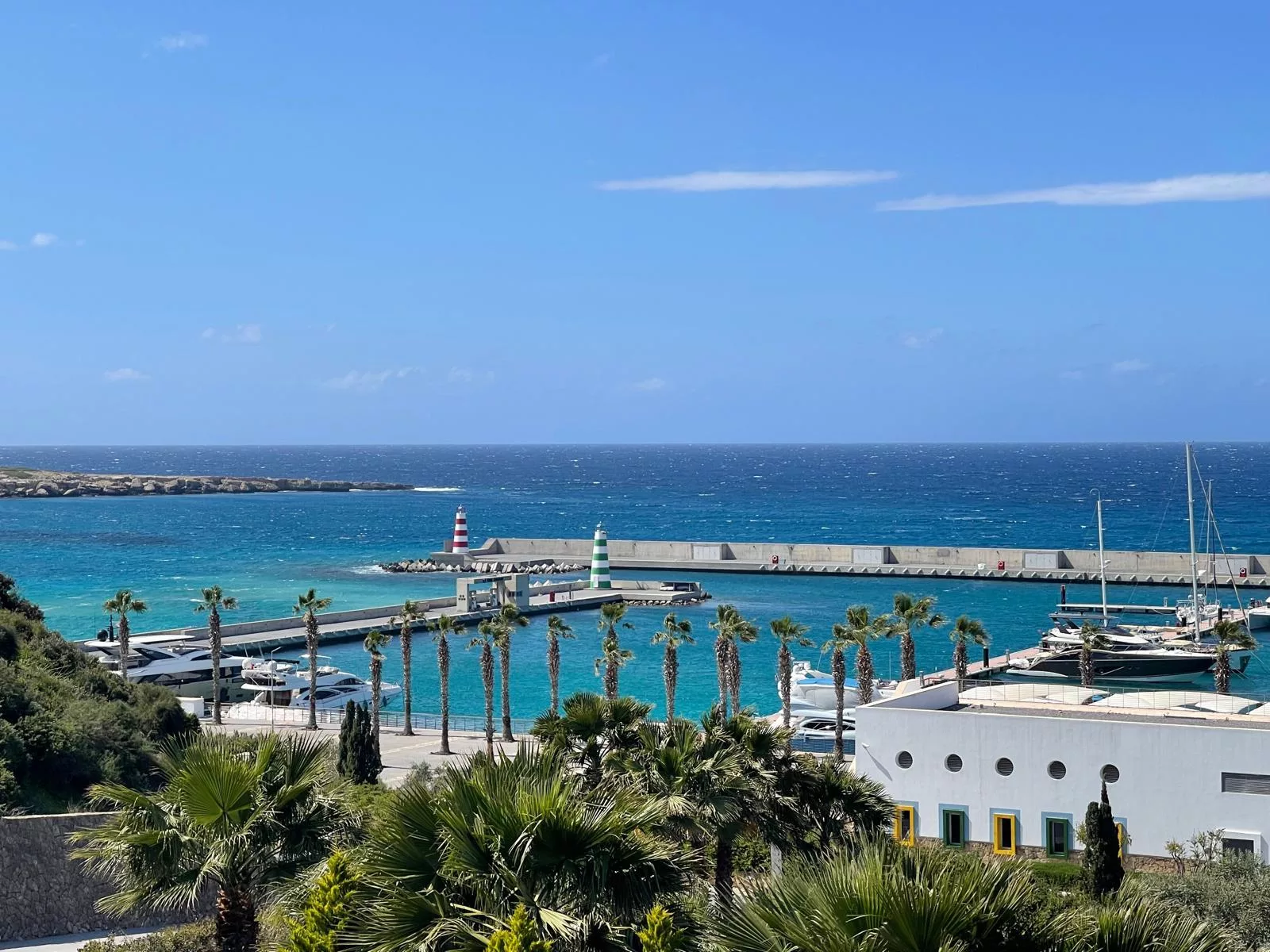 Yachthafen in Nordzypern mit Segelbooten, Palmenpromenade und Leuchttürmen an der Hafeneinfahrt